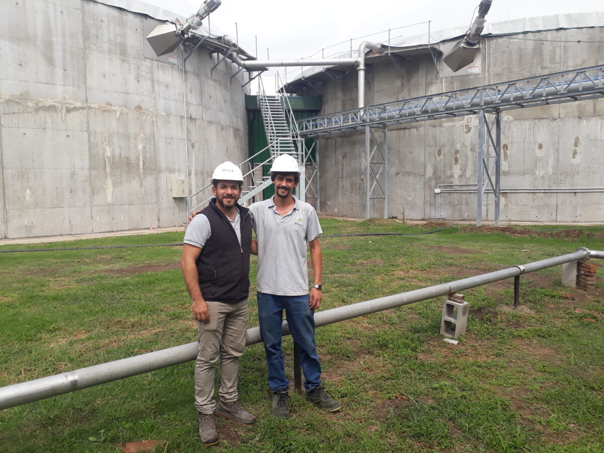 Ezequiel Weibel (izq.) y Ezequiel Tamburrini de pie con dos de los tres biomotores de fondo en Zárate, a 90 kilómetros de la capital argentina, que convertirán residuos de la industria agroalimentaria en biogás.  AMIGOS: Daniel Gutman / 